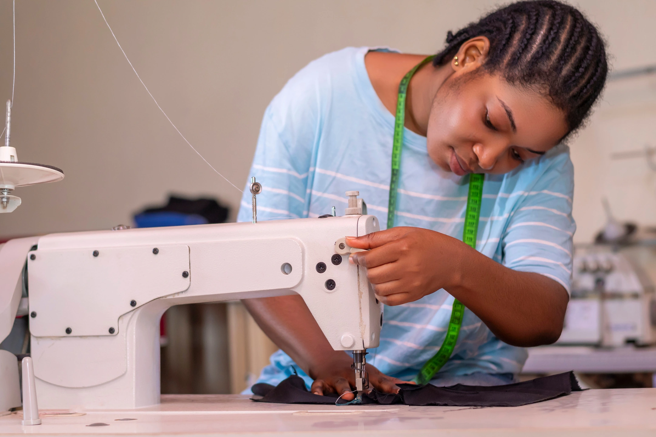 Une artisane LikeDress confectionne un vêtement à la machine à coudre.